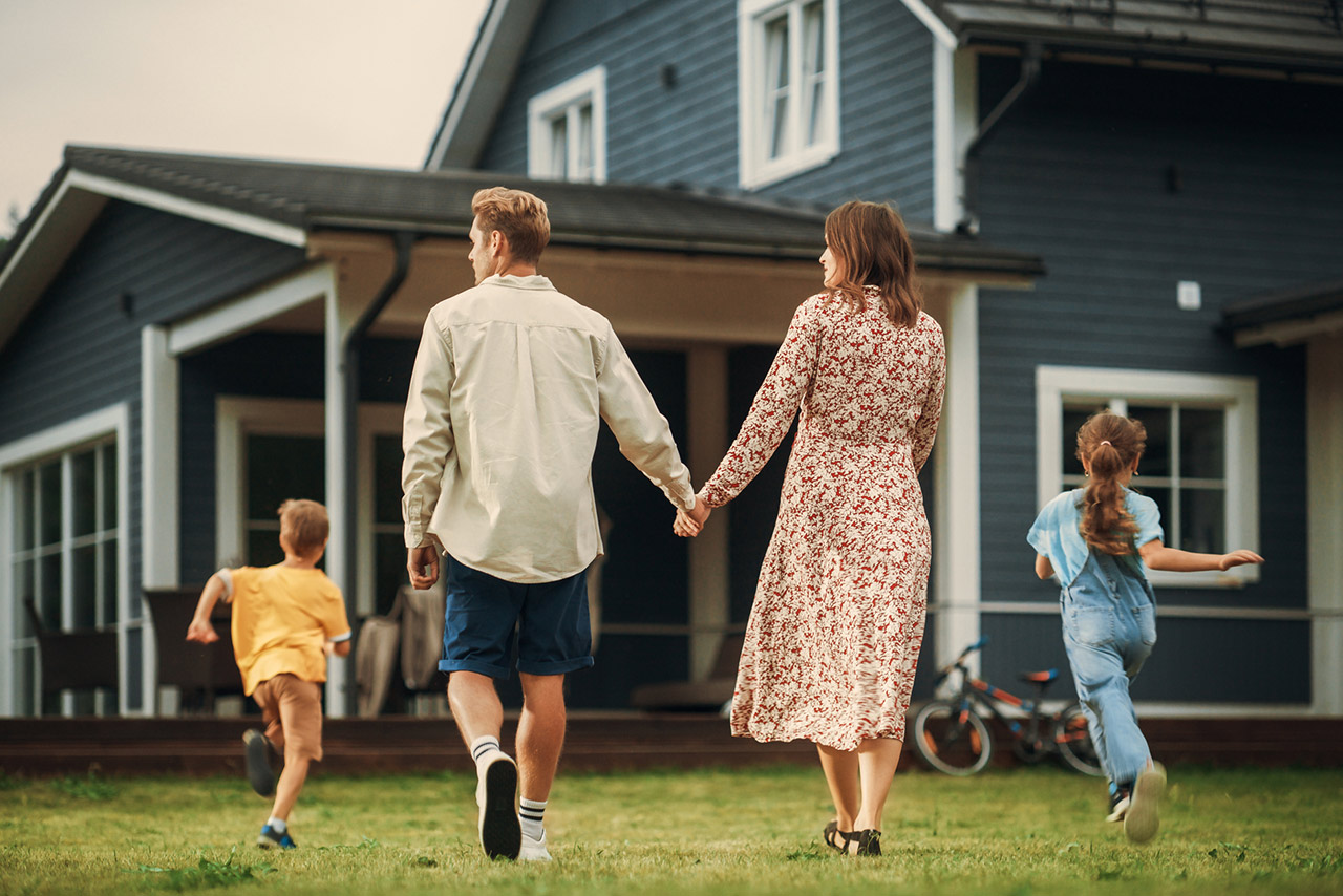 Young couple walking towards a country house with their two children