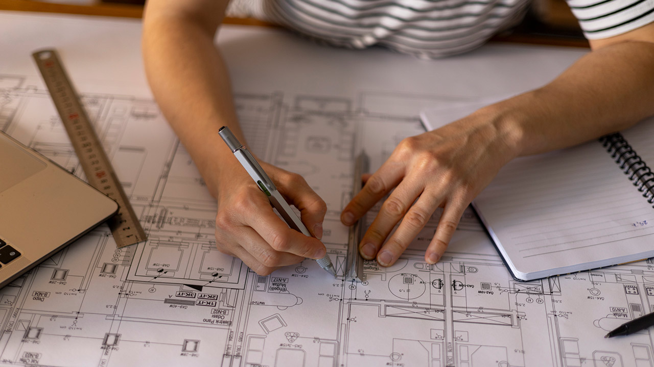 Architect working on a construction project, drawing blueprints using a ruler and a technical pen