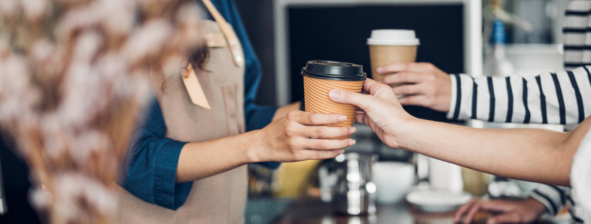 Barista served take away hot coffee cup to customer at counter bar in cafe restaurant