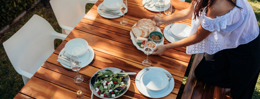 Top view of woman setting food on wooden table for housewarming party.